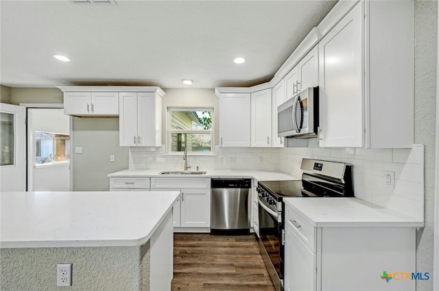 212 S Walnut Ave, Luling, TX 78648 - kitchen with appliances with stainless steel finishes, dark wood-style flooring, white cabinetry, tasteful backsplash, and light countertops