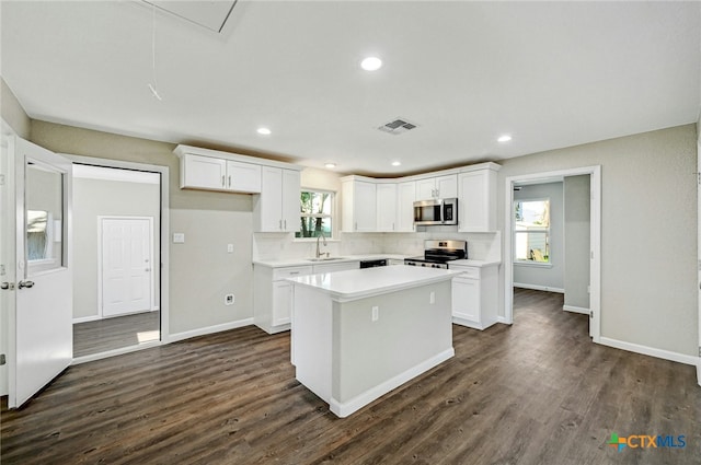 212 S Walnut Ave, Luling, TX 78648 - kitchen with appliances with stainless steel finishes, a center island, white cabinets, dark wood-style flooring, and light countertops