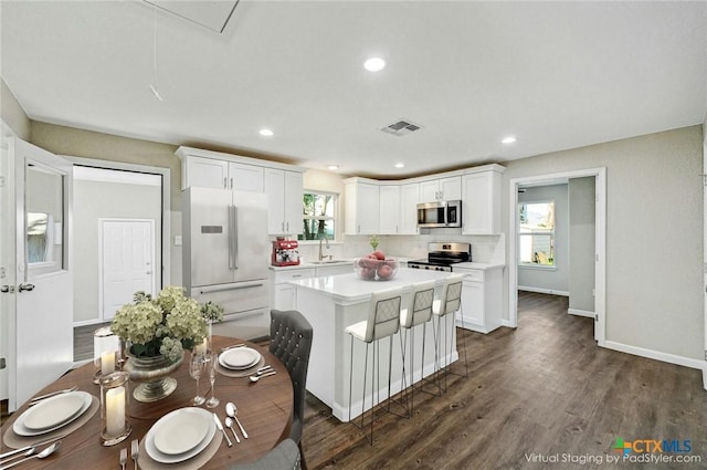 212 S Walnut Ave, Luling, TX 78648 - kitchen with appliances with stainless steel finishes, light countertops, white cabinetry, dark wood finished floors, and a center island