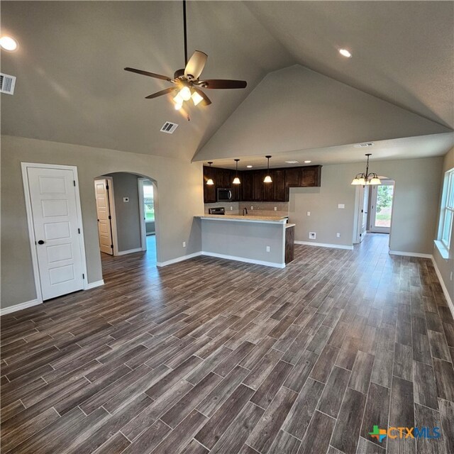 unfurnished living room featuring dark wood-type flooring, high vaulted ceiling, and ceiling fan with notable chandelier