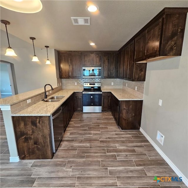 kitchen featuring stainless steel appliances, a sink, backsplash, and dark brown cabinetry
