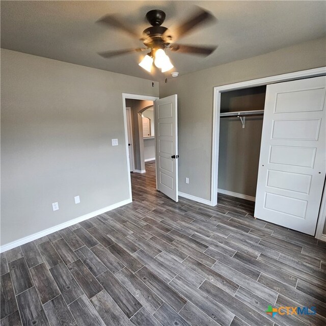 unfurnished bedroom with dark wood-type flooring, a closet, and ceiling fan