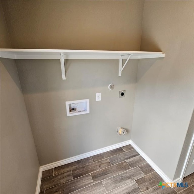 clothes washing area with hookup for an electric dryer, hookup for a washing machine, wood finish floors, and baseboards