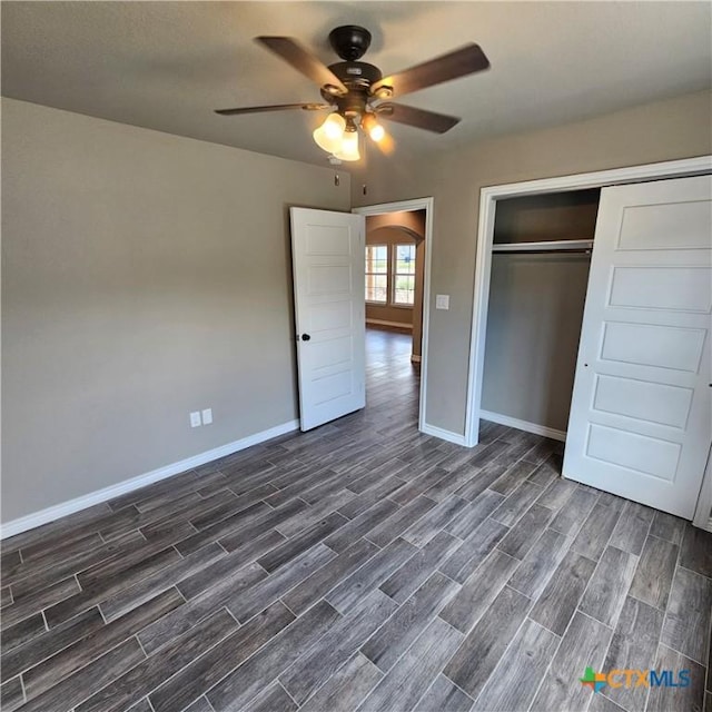 unfurnished bedroom with dark wood-style floors, baseboards, a closet, a ceiling fan, and arched walkways