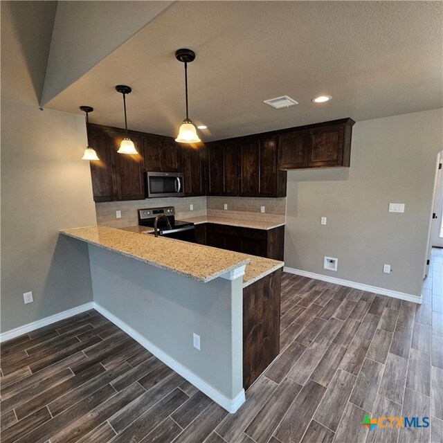 kitchen with stainless steel appliances, kitchen peninsula, hanging light fixtures, dark hardwood / wood-style floors, and dark brown cabinets