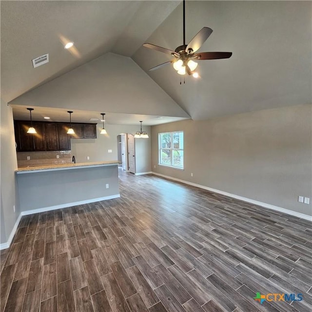 unfurnished living room featuring dark wood-style floors, ceiling fan, baseboards, arched walkways, and high vaulted ceiling