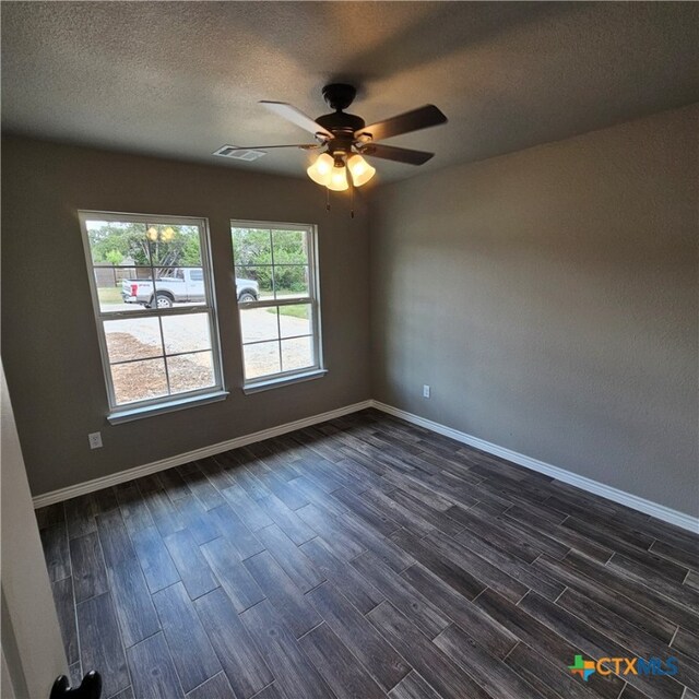 empty room featuring a textured ceiling, dark wood-type flooring, and ceiling fan