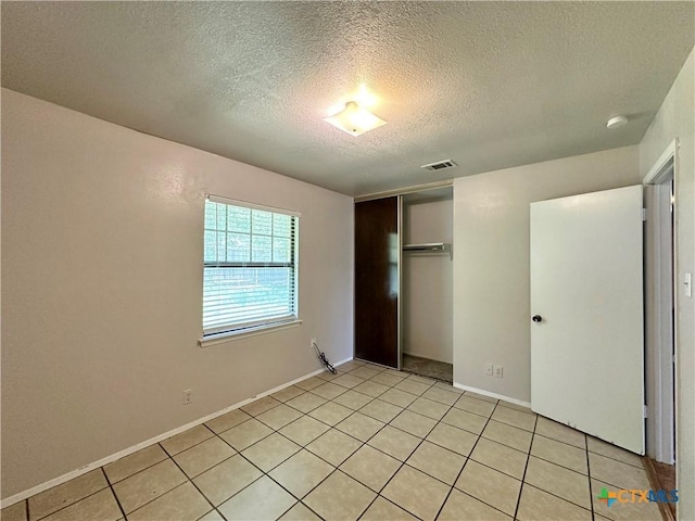 unfurnished bedroom with light tile patterned flooring, a closet, and a textured ceiling