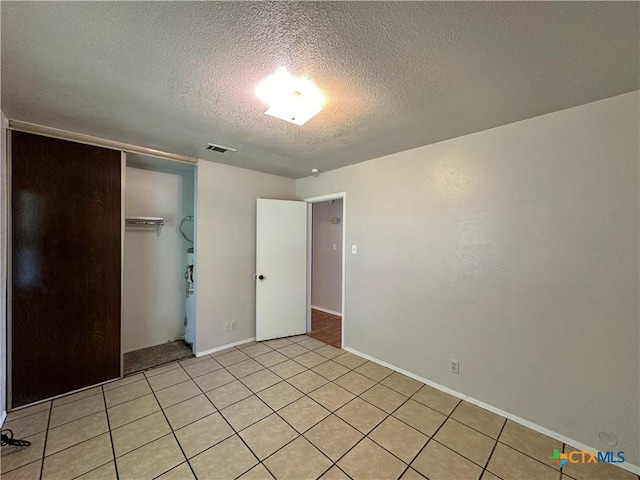 unfurnished bedroom featuring light tile patterned floors, a textured ceiling, and a closet