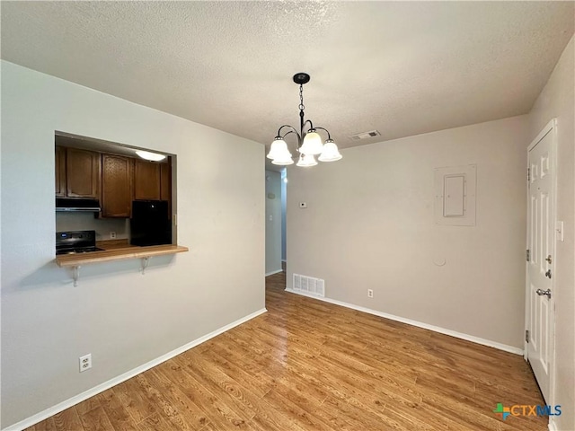 interior space with black refrigerator, decorative light fixtures, light wood-type flooring, a textured ceiling, and electric stove