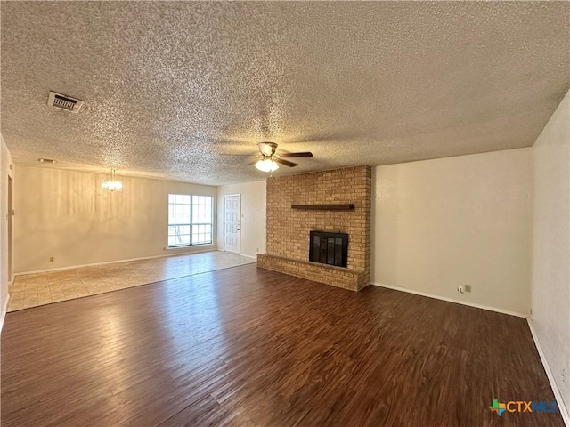 unfurnished living room with ceiling fan, a fireplace, dark hardwood / wood-style floors, and a textured ceiling