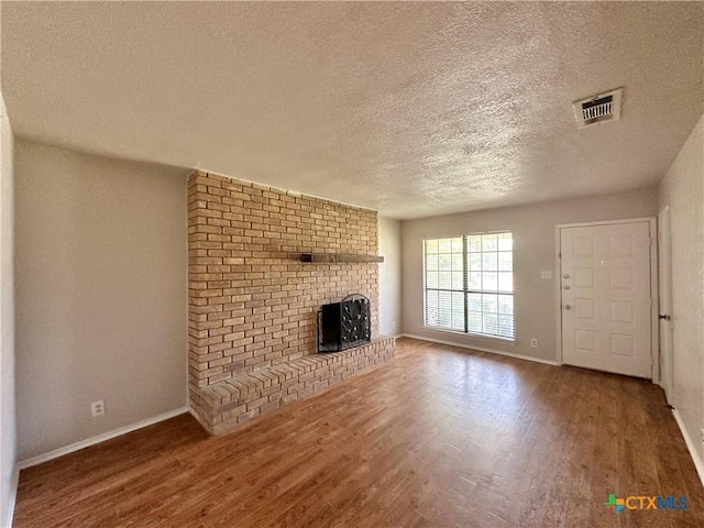 unfurnished living room with wood-type flooring, a textured ceiling, and a fireplace