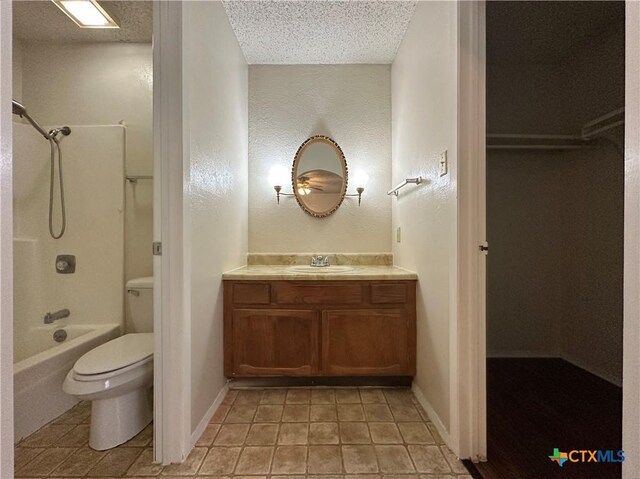 full bathroom featuring shower / bathing tub combination, vanity, a textured ceiling, tile patterned floors, and toilet