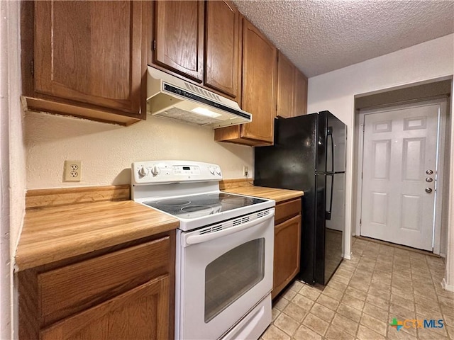 kitchen with electric stove, black refrigerator, butcher block counters, and a textured ceiling