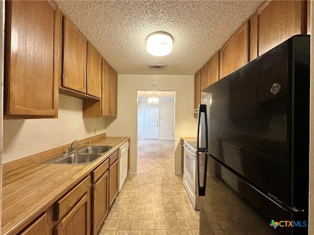 kitchen with pendant lighting, sink, white appliances, and a textured ceiling