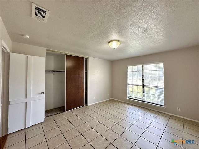 unfurnished bedroom featuring light tile patterned floors, a textured ceiling, and a closet