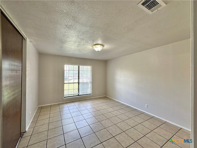 tiled empty room with a textured ceiling