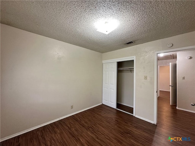 unfurnished bedroom with dark wood-type flooring, a closet, and a textured ceiling