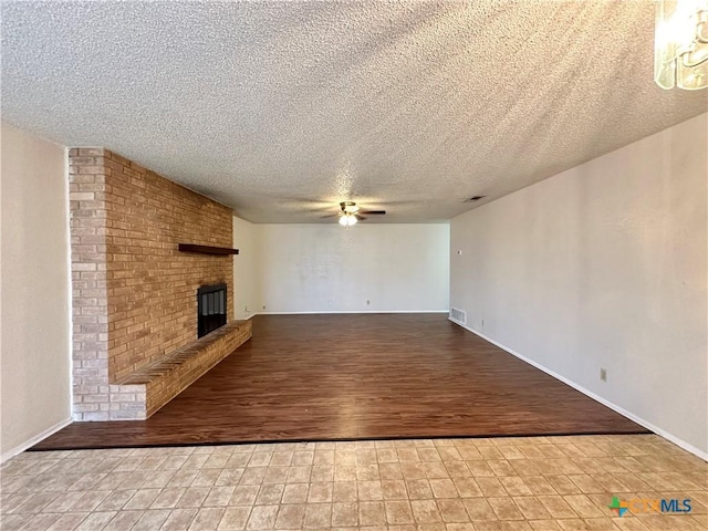 unfurnished living room featuring ceiling fan, a fireplace, and a textured ceiling