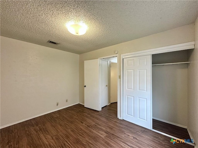 unfurnished bedroom featuring dark hardwood / wood-style floors, a closet, and a textured ceiling