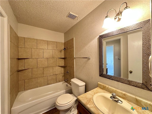 full bathroom with vanity, toilet, tiled shower / bath combo, and a textured ceiling