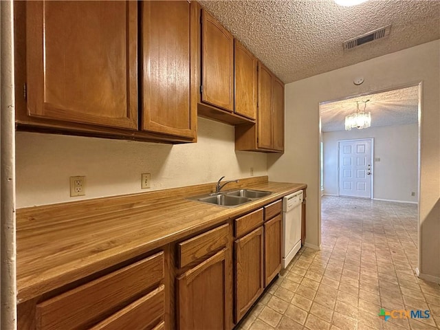 kitchen with sink, white dishwasher, a notable chandelier, a textured ceiling, and decorative light fixtures