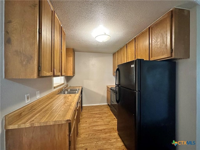 kitchen with sink, black appliances, a textured ceiling, and light wood-type flooring