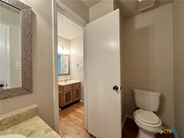 bathroom featuring vanity, hardwood / wood-style floors, toilet, and a textured ceiling