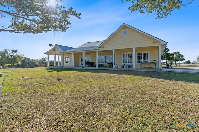 rear view of house featuring a lawn and a porch