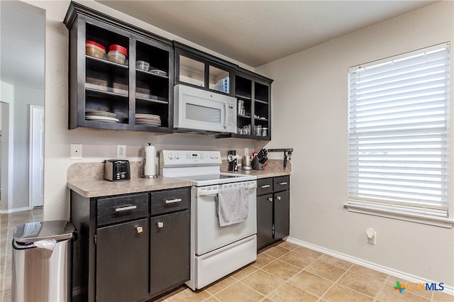 kitchen with white appliances, a textured ceiling, and light tile patterned floors