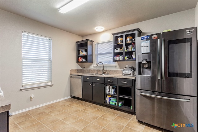 kitchen featuring a wealth of natural light, a textured ceiling, sink, and appliances with stainless steel finishes