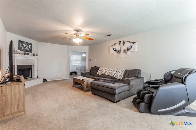 carpeted living room featuring a textured ceiling, ceiling fan, and a fireplace