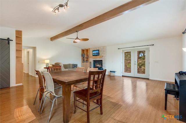 123 E Sierra Cir, San Marcos, TX 78666 - dining space featuring a ceiling fan, a stone fireplace, wood finished floors, and a barn door