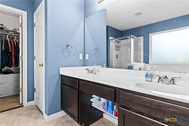 bathroom with tile patterned flooring, vanity, and walk in shower