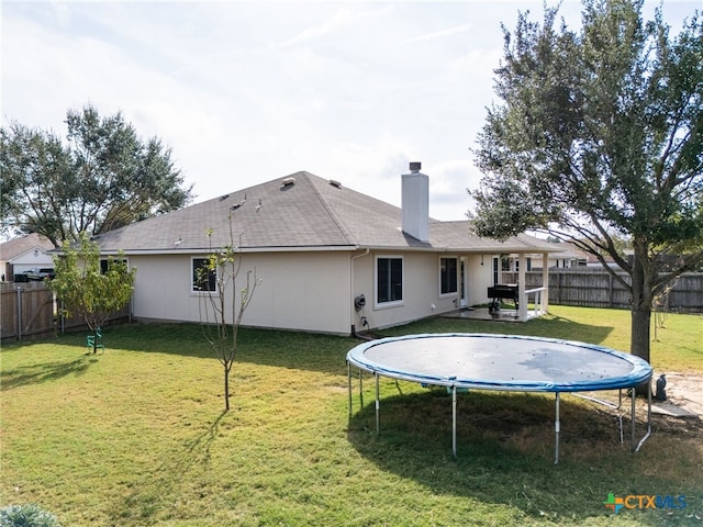 rear view of house featuring a lawn and a trampoline