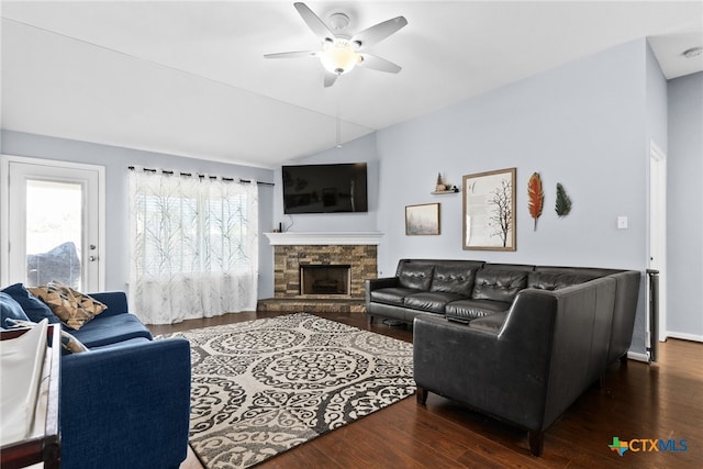 living room featuring vaulted ceiling, a stone fireplace, ceiling fan, and dark wood-type flooring