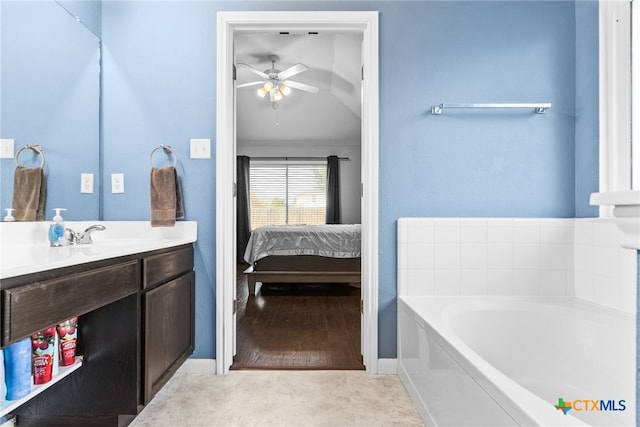 bathroom with ceiling fan, a washtub, vanity, and wood-type flooring