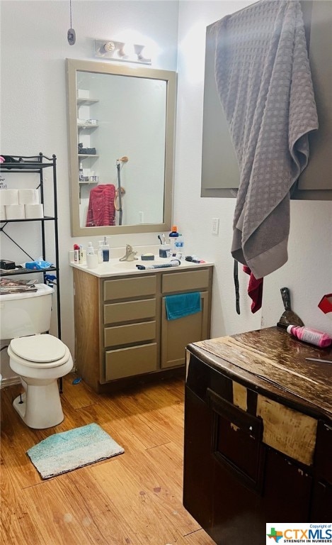 bathroom featuring wood-type flooring, toilet, and vanity