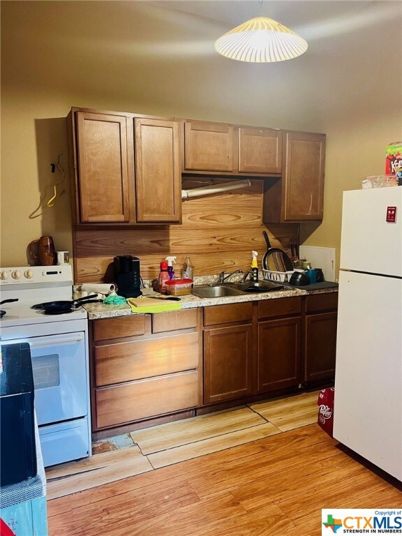 kitchen with white appliances, sink, and light hardwood / wood-style floors