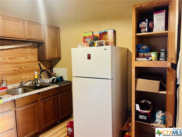 kitchen with light wood-type flooring, white refrigerator, and sink