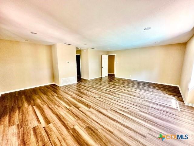 spare room with baseboards and wood finished floors