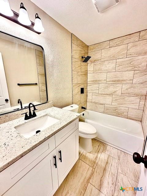 full bathroom with a textured ceiling, toilet, vanity, a textured wall, and shower / bathtub combination