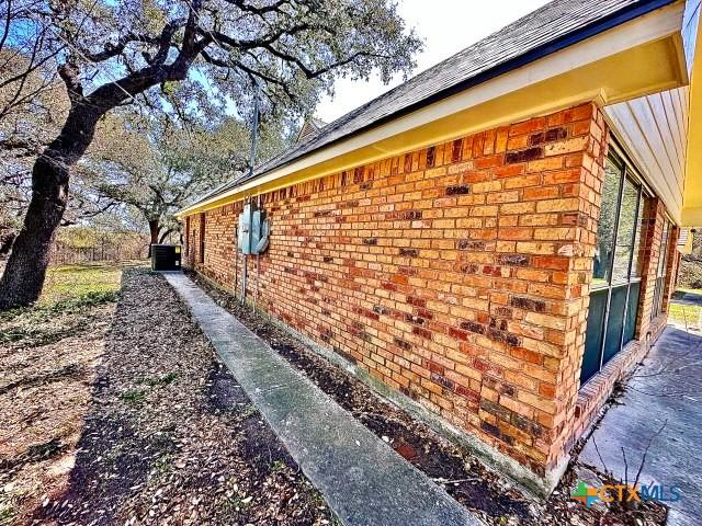 view of property exterior featuring brick siding and central AC
