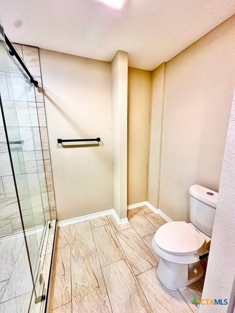 full bath featuring toilet, a stall shower, and baseboards