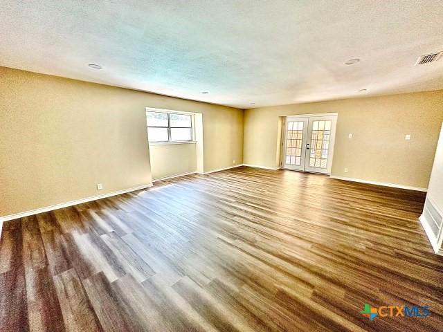 unfurnished room featuring french doors, wood finished floors, a textured ceiling, and visible vents