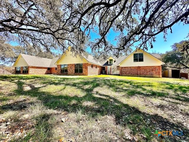 back of property with brick siding and a yard