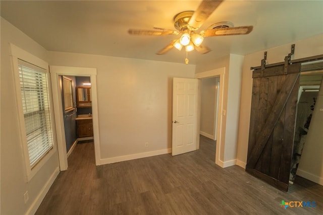 3001 Hummingbird St, Victoria, TX 77901 - unfurnished bedroom featuring dark wood-style flooring, a barn door, and a ceiling fan