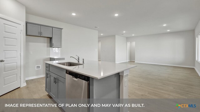 kitchen featuring sink, a kitchen island with sink, gray cabinets, stainless steel dishwasher, and light hardwood / wood-style flooring