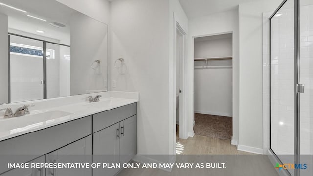 620 Radley Rd, Lockhart, TX 78644 - bathroom with a walk in closet, a stall shower, double vanity, wood finished floors, and baseboards