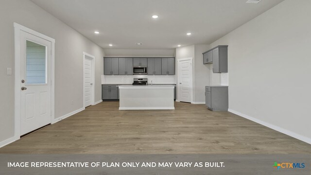 kitchen featuring a kitchen island, gray cabinetry, light hardwood / wood-style floors, and stainless steel appliances